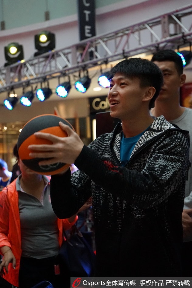 翟晓川在展板前签名留影，神情专注而放松，身后队友的目光汇聚一处，构成一幅团结一心的画面