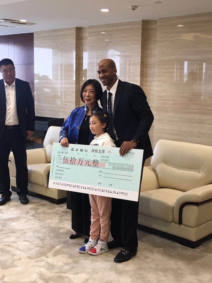 年过七旬的张阿姨面带慈祥笑容，双手郑重地将一张巨大的五十万元支票展板递到马布里面前，眼神中满是对偶像的关爱与支持。