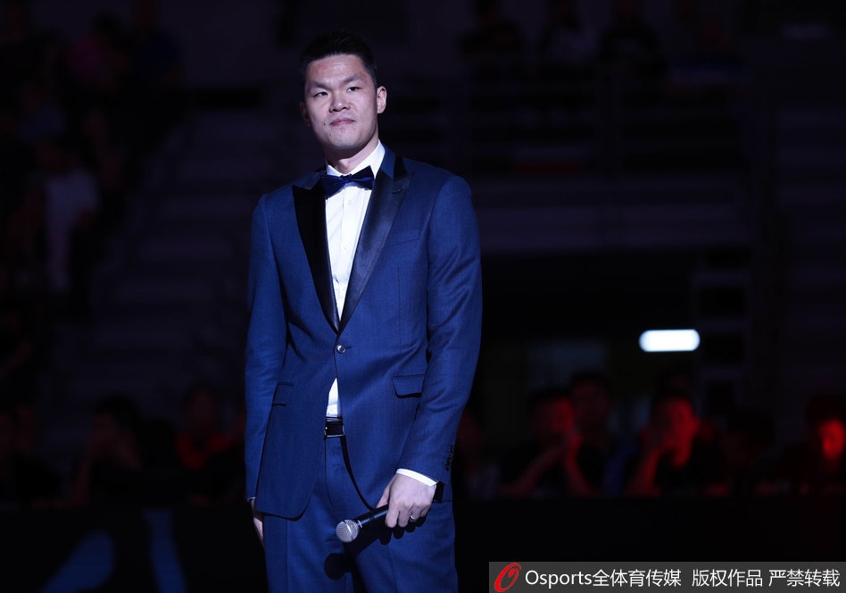 站在球场中央进行致辞的朱芳雨，手持话筒，神情专注而真挚，背后是坐无虚席、为他欢呼的球迷，他用幽默的话语感谢了所有人，为这段球员生涯画上完美句号。