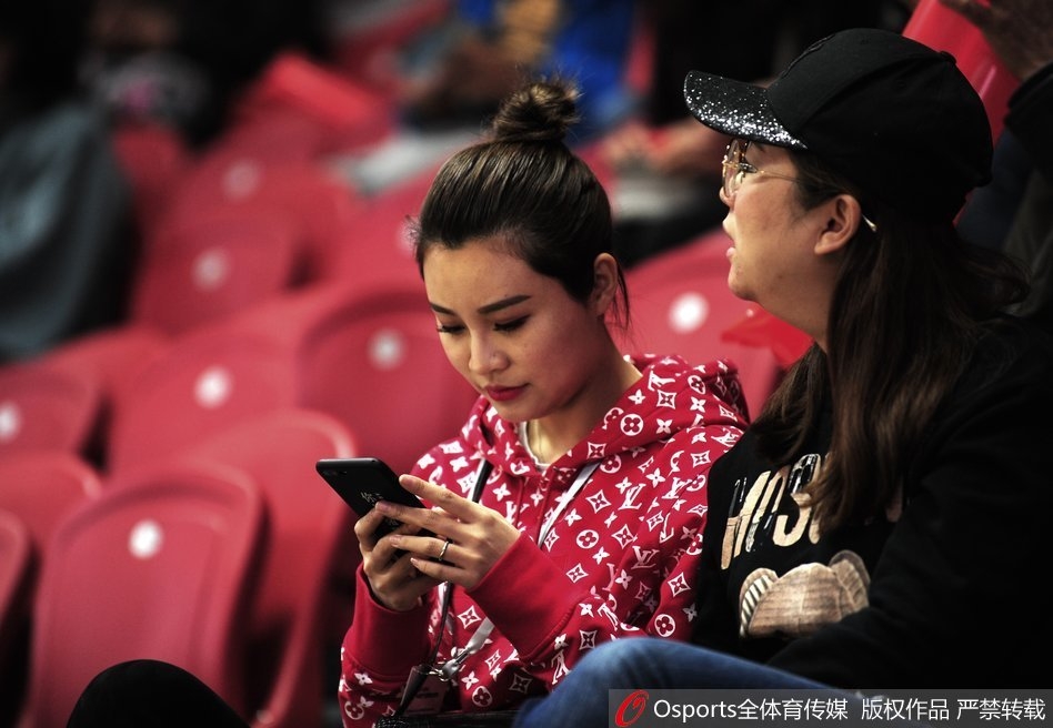 看台上的李根妻子与友人热聊,她时而掩面微笑,时而紧张凝视球场,表情随着比赛的跌宕起伏而变化,内心牵挂可见一斑。