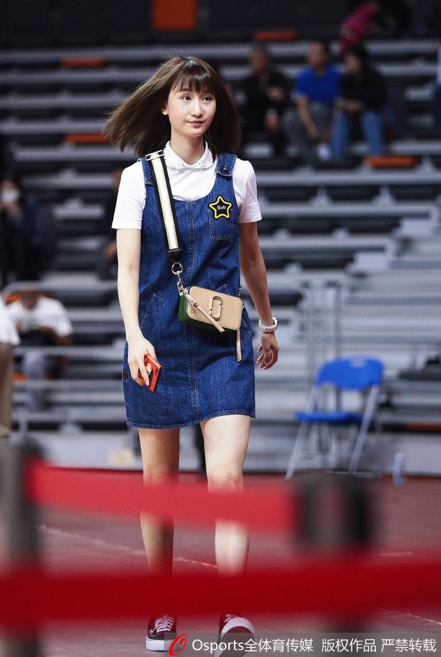 比赛间隙，刘美静坐在看台一角，身姿挺拔，目光越过人群，温柔地锁定在球场上的某个身影上，仿佛周遭的喧嚣都与她无关。