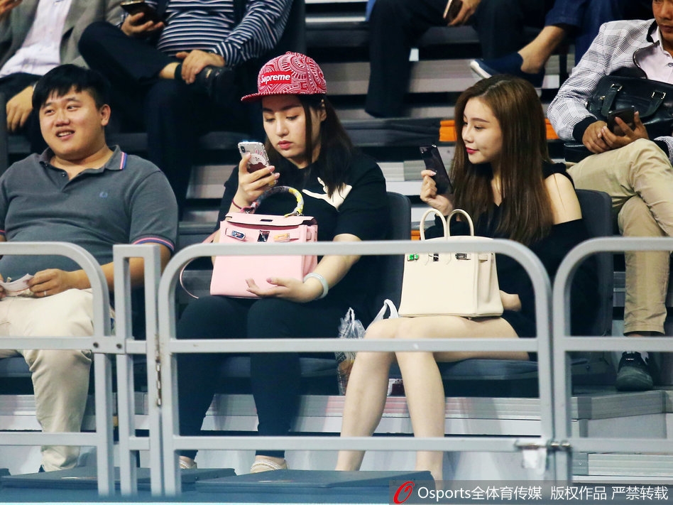 一位面容清秀的女球迷坐在场边,目光越过喧嚣,专注地望向赛场方向,仿佛与周遭的紧张气氛隔绝。