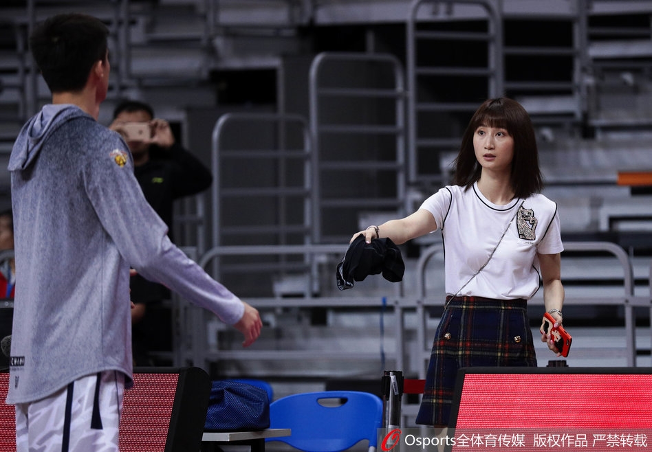 孙桐林的妻子端坐在篮架后方的家属区,眼神紧紧跟随着场内正在热身的丈夫,面带一丝紧张与期待,仿佛在用目光传递着无声的支持