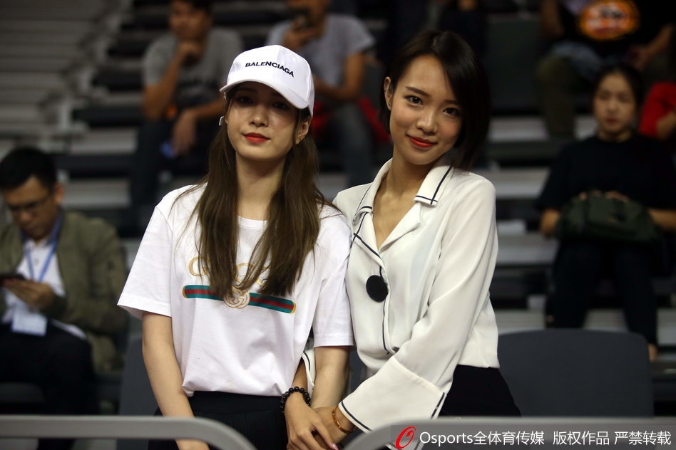 一位身穿浅色外套的女球迷,在人群中安静地注视着球场,眼神清澈,成为激烈赛事旁一道温婉的风景线。