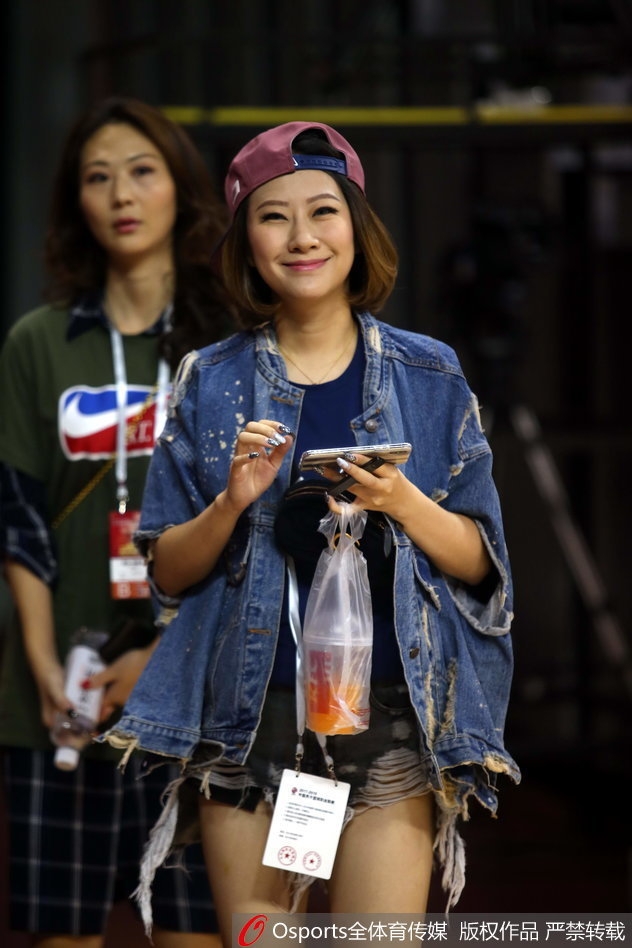 一位笑起来阳光灿烂的女球迷,对着镜头大方地展示着手中的助威棒,她的笑容为这场紧张的大战增添了无限暖意。