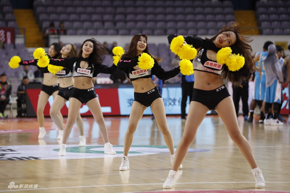 镜头特写一位啦啦队员的专注表情，她手举金色花球目视前方，额头渗出汗珠却依然保持甜美微笑，职业精神令人动容