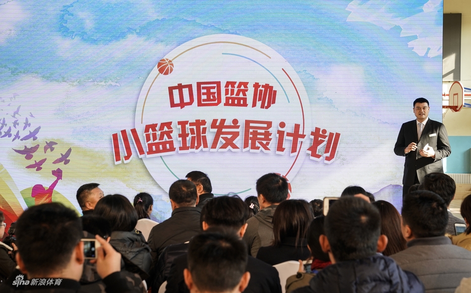 几位领导嘉宾站在摆满捐赠小篮球和篮架的桌子后，准备将这些为孩子们量身定做的体育器材送到学校手中。