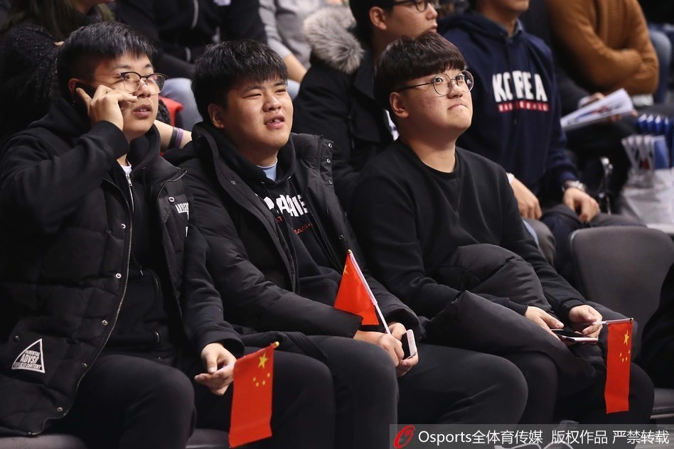 赛场边的看台上,一名年轻的中国球迷脸上洋溢着自豪的笑容,他身体前倾,奋力挥舞着手中的小型五星红旗,旗帜的红色与他脸上的兴奋交相辉映。