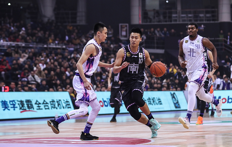 南区明星队球员在场上快速反击，身后北区防守球员奋力回追，整个球馆座无虚席，气氛热烈