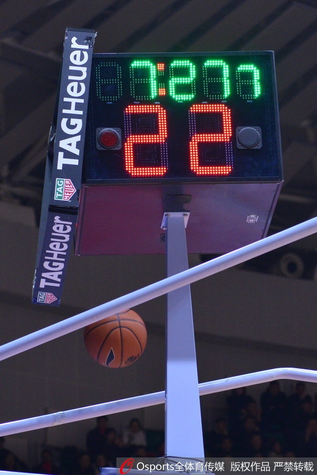 易建联在对方内线球员的包夹下强行起跳，眼神中透露出不甘与坚毅，身后的记分牌闪烁着新疆队领先的比分，记录着这位核心球员的孤独奋战