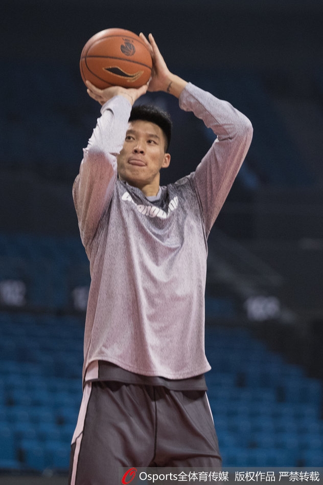 训练间歇，易建联拿起水瓶补充水分，汗水浸湿了球衣，但他的眼神依旧坚毅地盯着远处的篮筐。