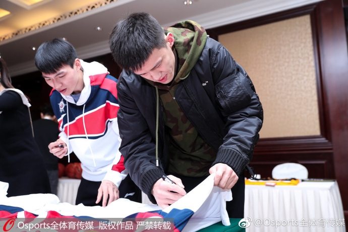 人气爆棚的签名区域，篮球和官方台历堆积如山，全明星球员们低首伏案，手中的签字笔在光滑的纸面和球面上游走，一旁的球迷们手持纪念品，目光中满是期待与兴奋。