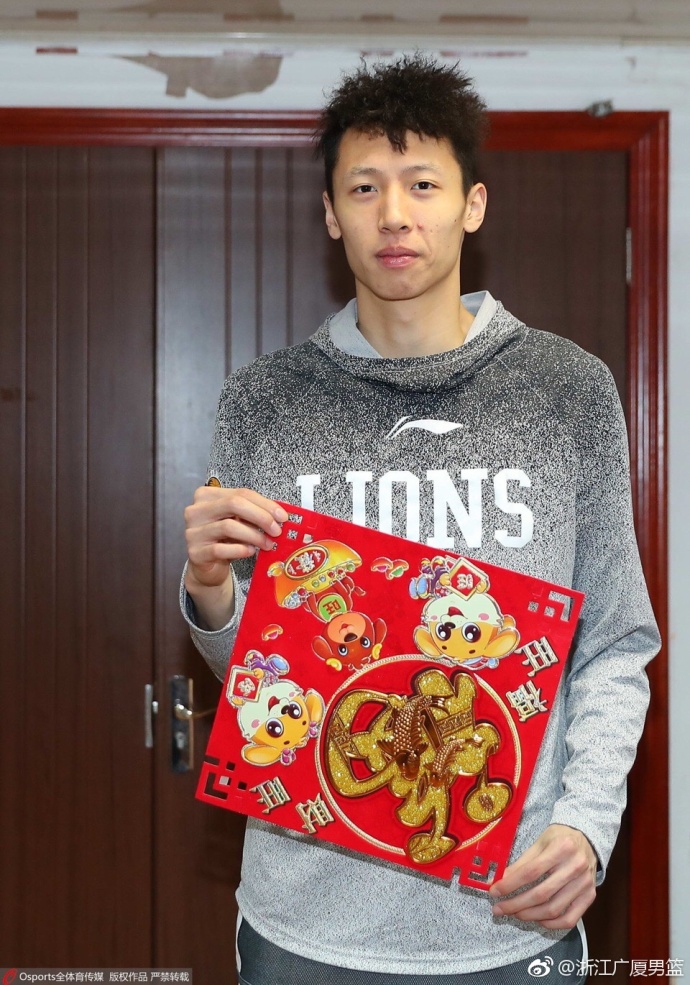 队长胡金秋手持火红福字,坚毅的眼神中透露出节日的温情,身后仿佛映照着黄龙体育馆的冠军旗帜