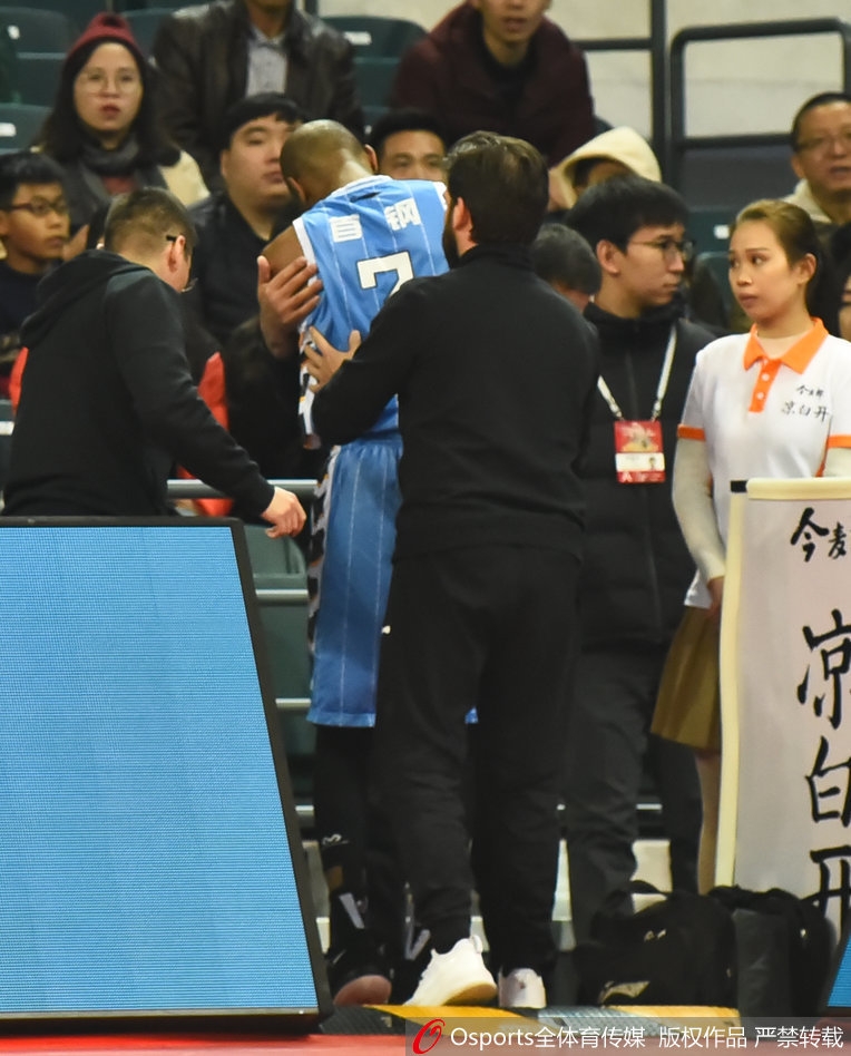 队医在更衣室通道紧急检查杰克逊的伤势，周围人员神情紧张而关切