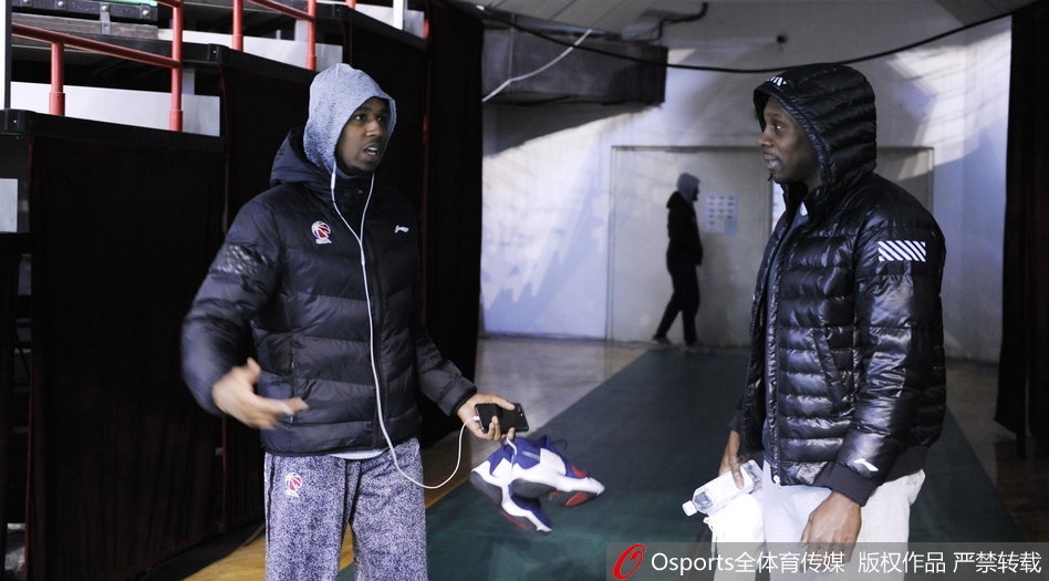 训练场上，两人并肩站立，神情专注地看向场地中央。他们穿着各自球队的训练服，在灯光的照射下，身影显得格外修长。