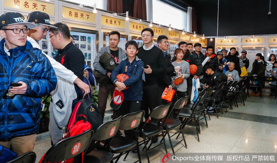 人山人海的签售大厅里，马布里坐在桌前专注地为球迷签名，背景墙上挂着他不同时期的经典照片，排队的球迷们井然有序地向前移动，手中拿着海报和纪念品，眼神中充满期待。