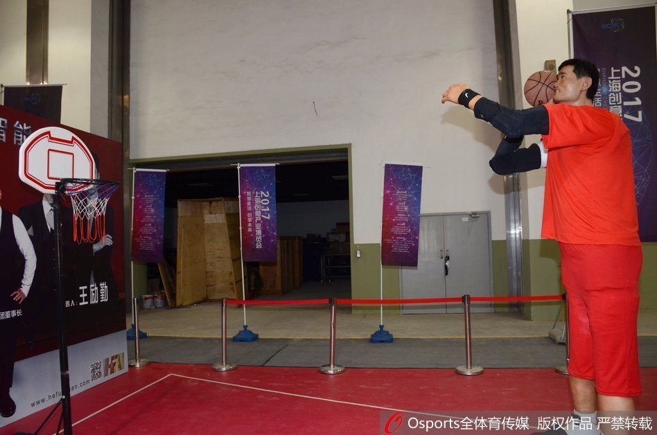 全景镜头下，机器人姚明与周围的观众形成鲜明对比，它面无表情却无比逼真，仿佛从科幻电影中走出的机械战警，静立在熙攘的人群之中。