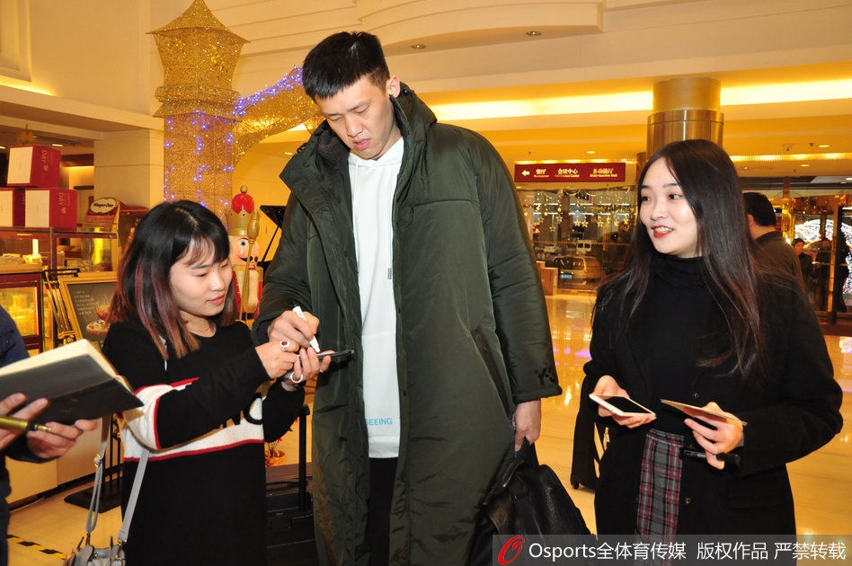 易建联一身休闲装扮走出通道，眼神深邃而坚定，面对济南球迷高举的手机和热情的呐喊，他微微颔首致意，仿佛在静谧中积蓄着内线的巨大能量。