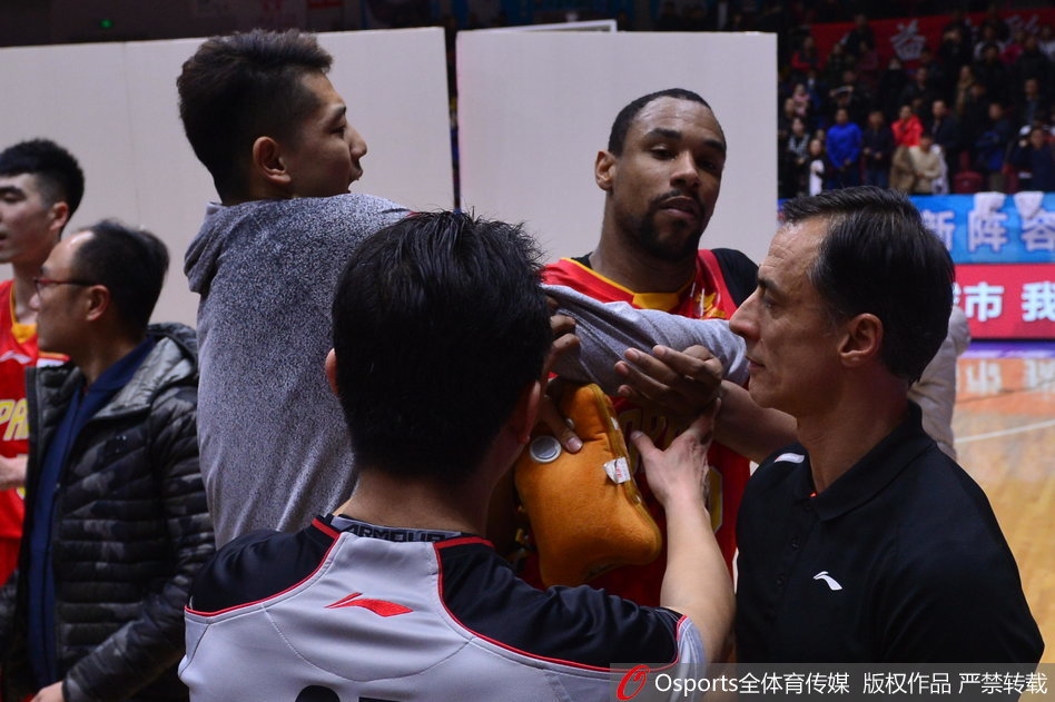 从侧面看去,萨林杰被围堵在人群中,他的眼神死死盯着新疆队球员离开的方向,双臂被队友紧紧锁住,肌肉紧绷,仿佛下一秒就要挣脱束缚。