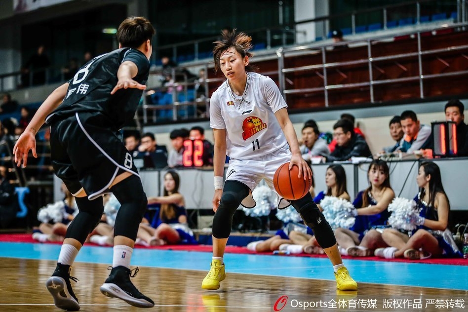 北京队主教练张云松在场边神情严峻地大声指挥着球员跑位，双手比划着战术手势，他的身后是坐满观众的看台，气氛热烈