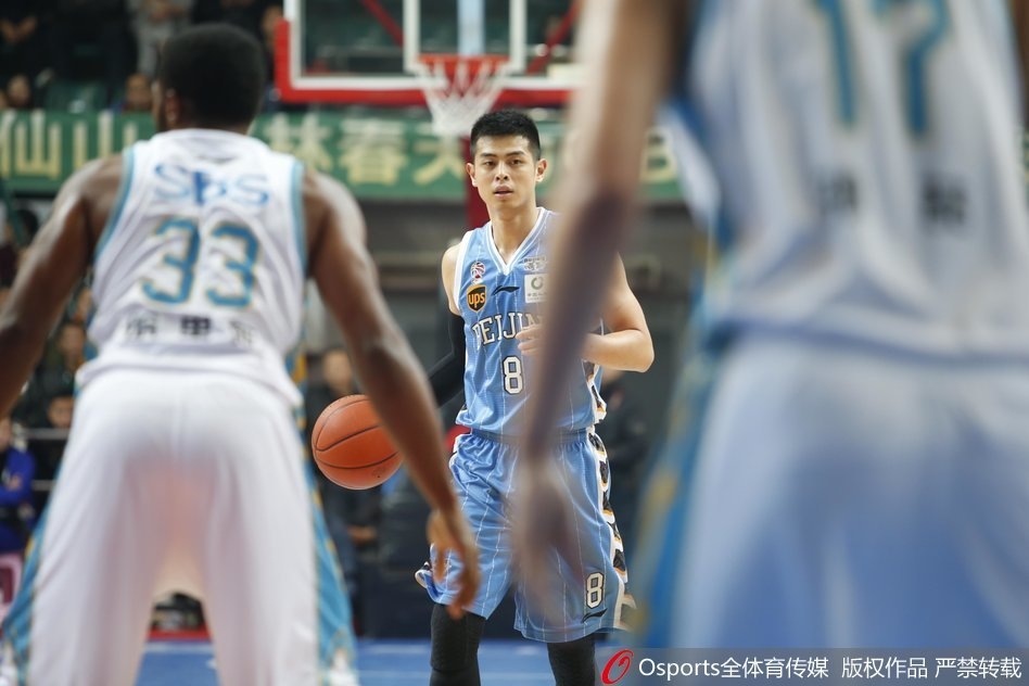 北京首钢球员吉喆张开双臂全力防守，福建王哲林持球伺机而动