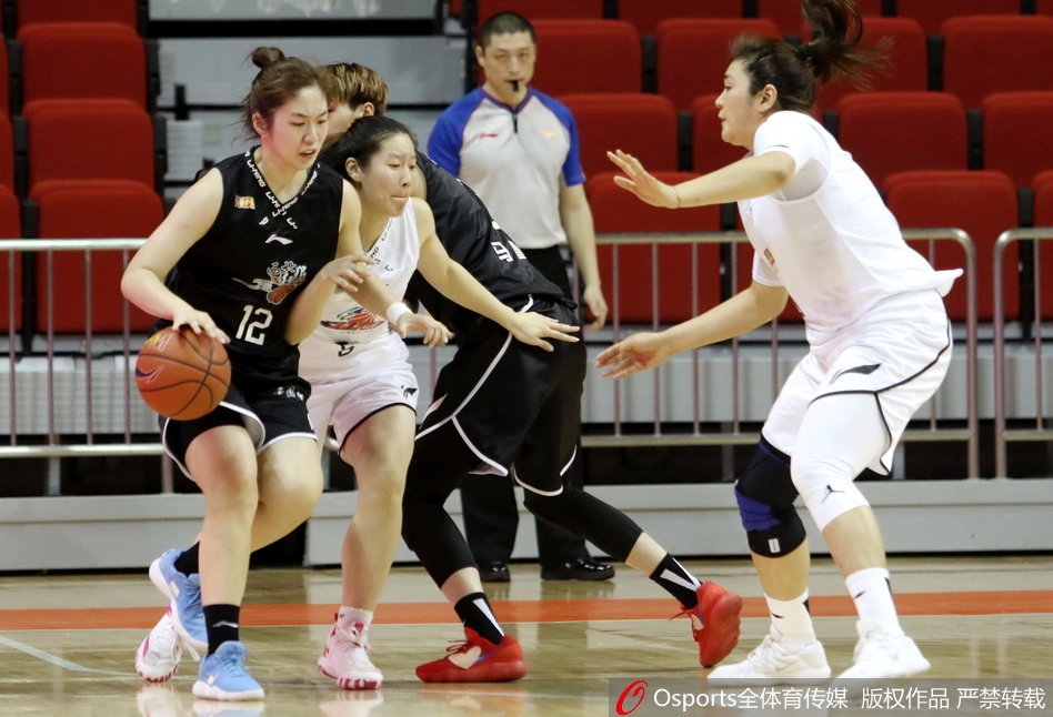 场边上海女篮的教练组在暂停期间，正拿着战术板给球员们布置关键的防守战术，球员们围成一圈认真聆听