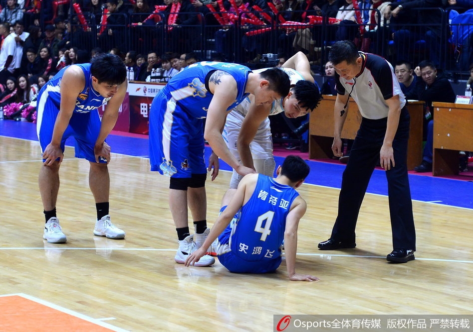 史鸿飞在拼抢后痛苦倒地，双手紧捂受伤部位，表情因剧痛而扭曲，一旁的江苏队队友焦急地低头查看他的伤情。