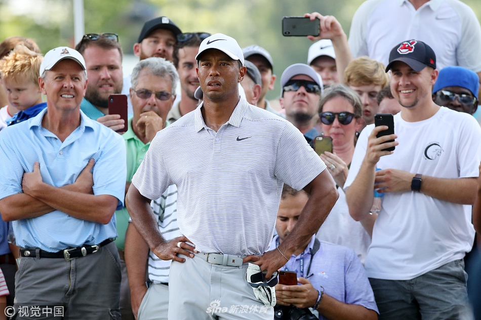 伍兹在第十六洞发球台全力挥杆，身体扭转充满力量，背景是火石球场开阔的景观。