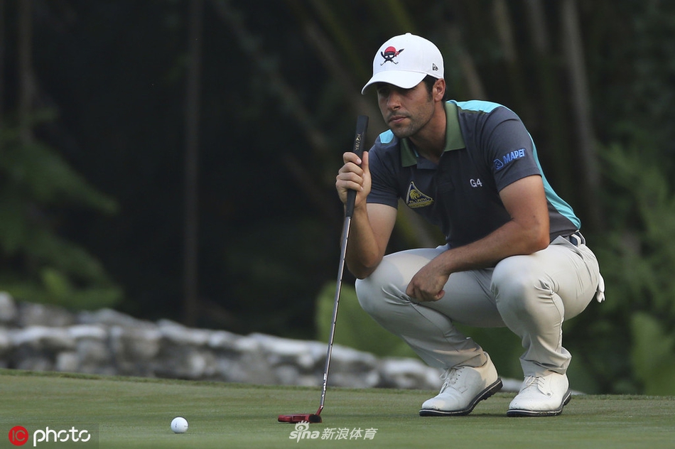 一位球手在果岭边细致地进行切杆准备，帽檐下目光如炬紧盯小白球