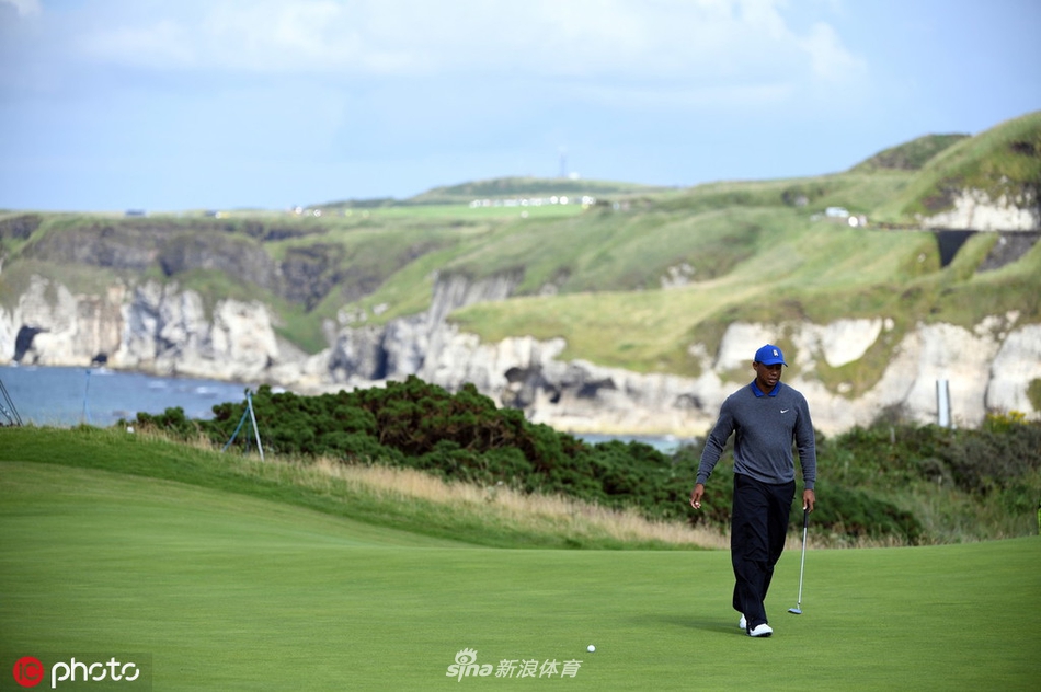 伍兹在长草中艰难处理一记棘手的球位,他眉头紧锁,身体姿态显示出背部不适带来的紧绷感,脚下是皇家波特拉什典型的滨海长草。