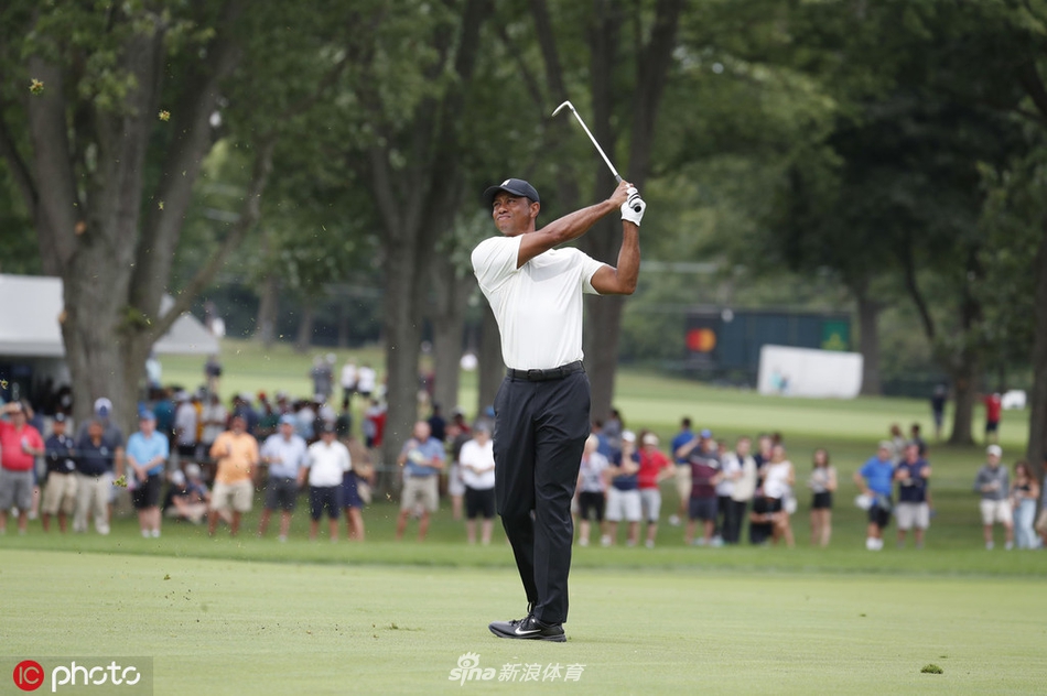 老虎伍兹在发球台上大力开球，身体充分扭转，目光紧盯着球飞出的方向
