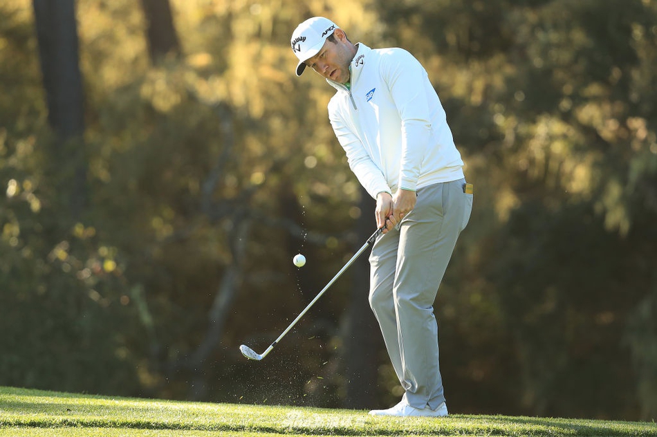 简森·戴伊在蒙特利半岛海岸球道的沙坑中救球,动作优雅而充满力量感。