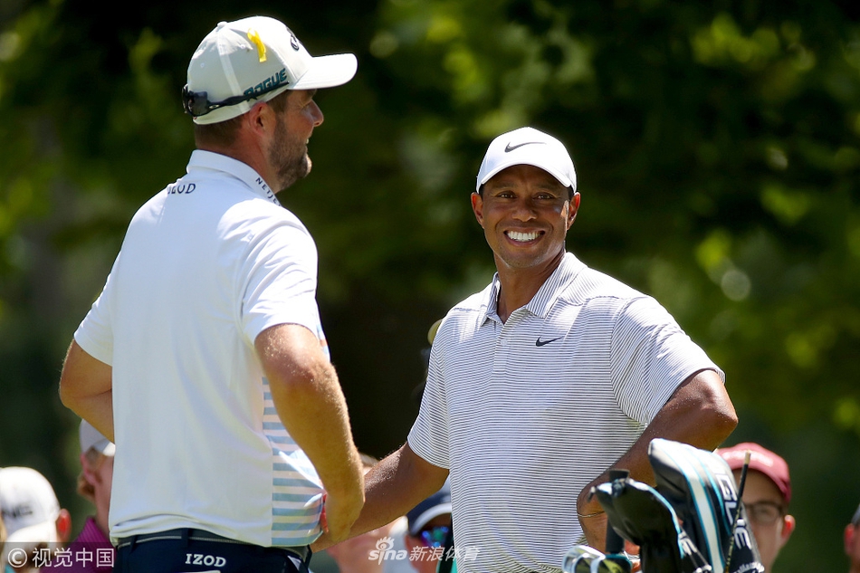 老虎伍兹在火石球场第十二洞果岭边凝神观察推杆线路，阳光洒在他专注的脸庞上。