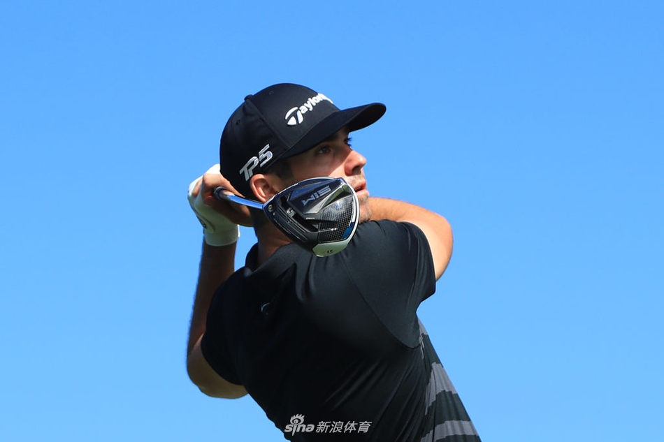 科林·森川在练习果岭上推杆,背景是茂密的热带植物与开阔的天空