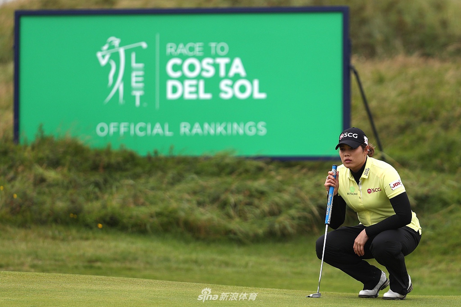 观众们聚集在陡峭的沙丘斜坡上，屏息凝神观看果岭上的推击，构成一幅生动的观赛图景。