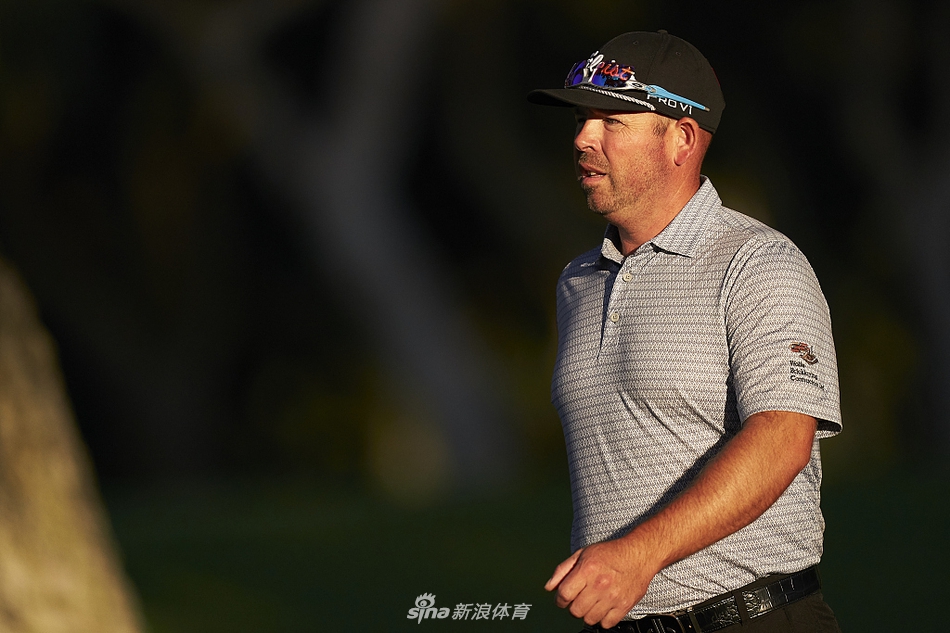 小白球在果岭上朝洞杯滚去的动态瞬间,背景是选手凝神屏息的期待身影与观众模糊的轮廓