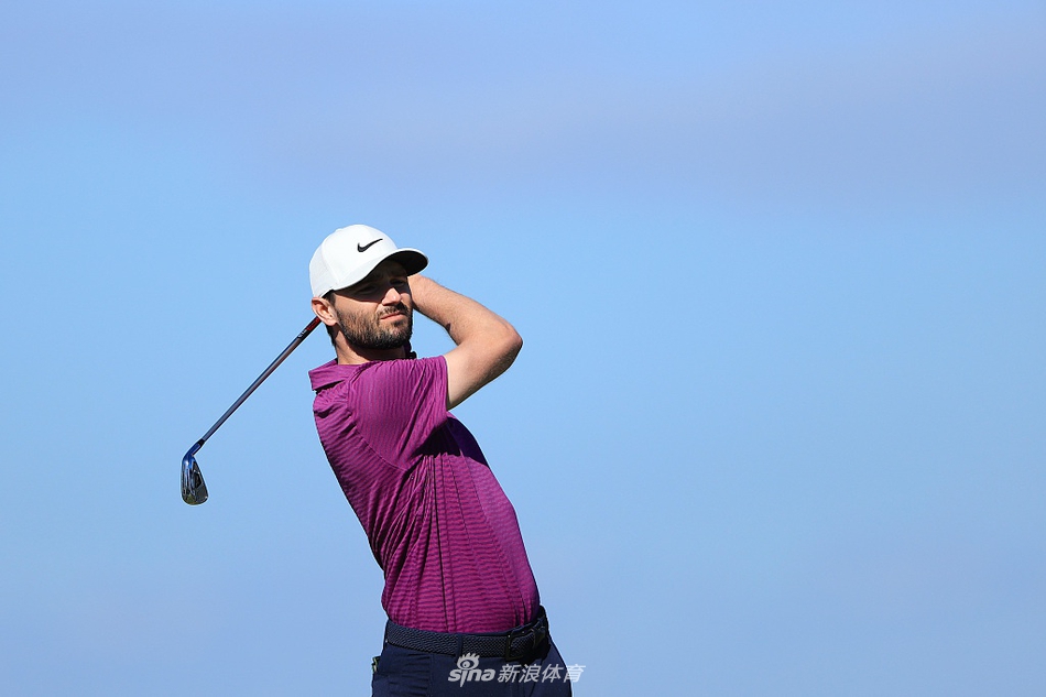 凯尔·斯坦利在全神贯注地观察果岭起伏，为下一推做精心准备，展现了职业球员的严谨。