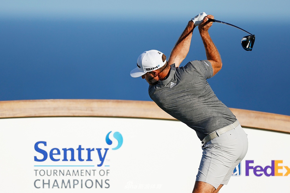 达斯汀·约翰逊在发球台全力开球，肌肉线条在阳光下勾勒出力量之美