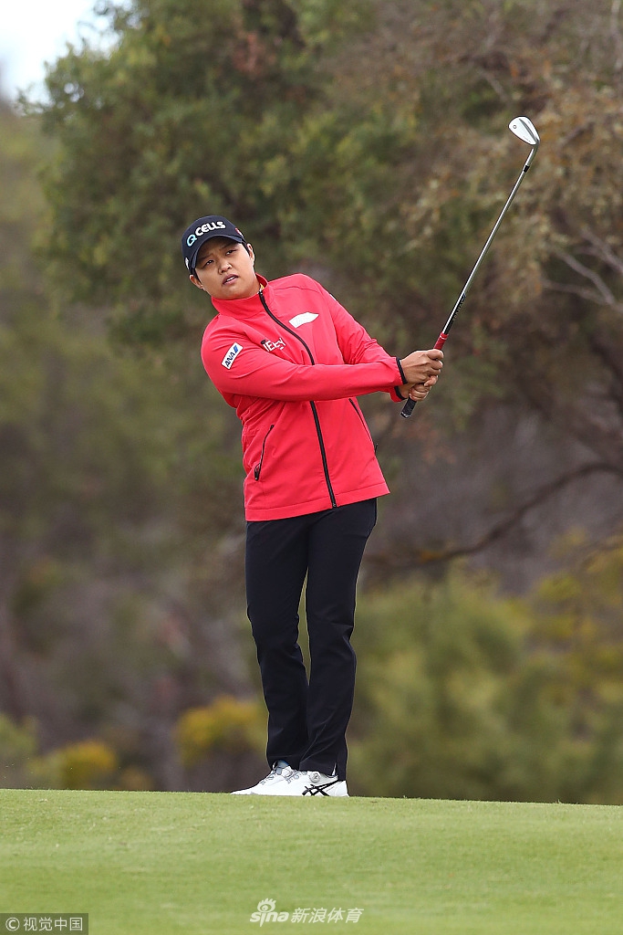 观众聚集在沙坑环绕的果岭旁，聚精会神地观看球员处理艰难球位，现场气氛紧张而投入。