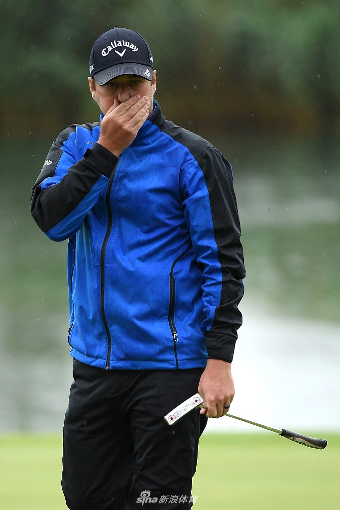 球童在狂风大雨中奋力撑起一把大伞，试图为球员创造一丝稳定的空间，展现了团队在逆境中的紧密协作。