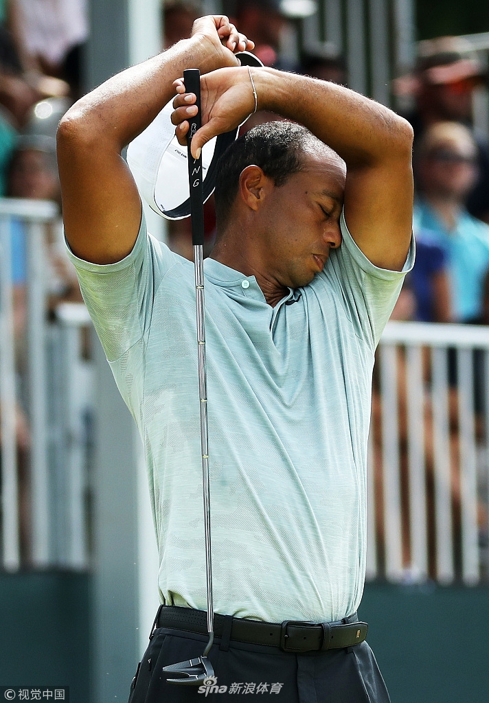 伍兹在开阔的球场上行走,蓝天绿草映衬着他孤独而坚定的背影。