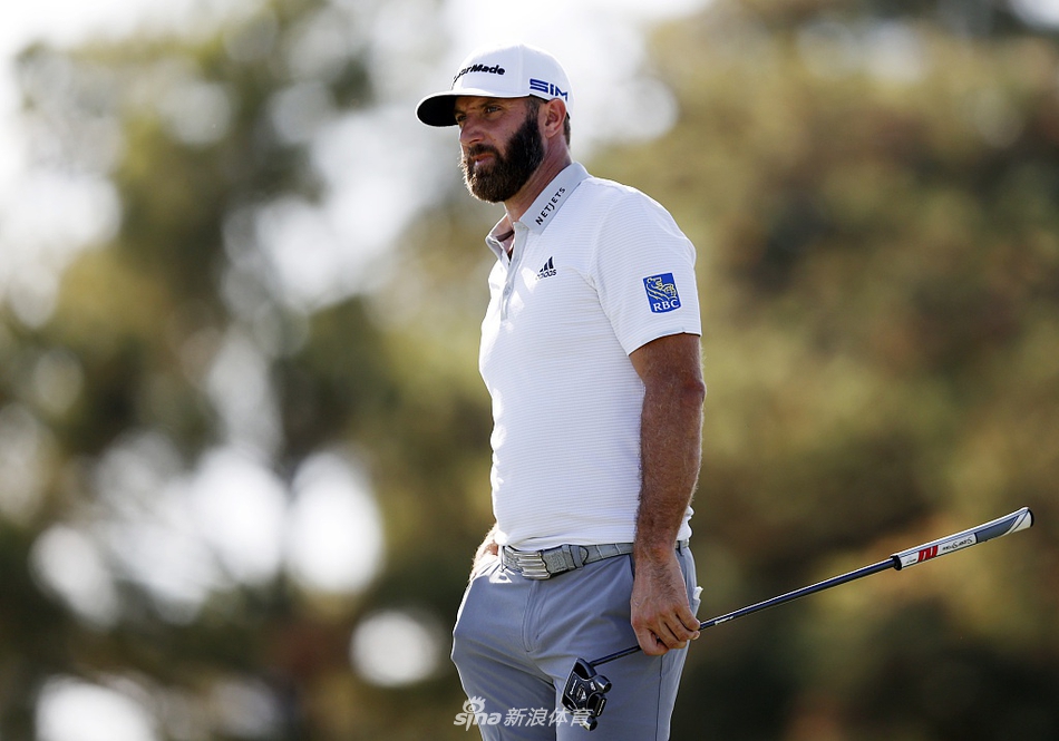 达斯汀·约翰逊在发球台凝神准备，身后是广阔的球道与成排的观众