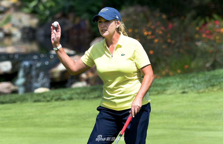 观众聚集在果岭周围，屏息凝神地观看球员推杆，赛场气氛紧张而又充满期待。