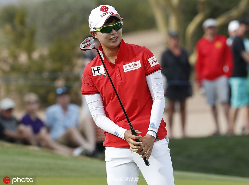 赛场远景，绿茵如毯的球道与蓝天白云相映成趣，构成一幅优美的运动画卷