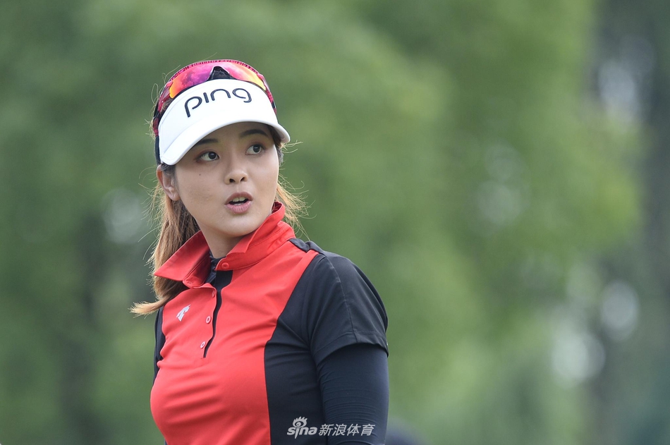 侯羽蔷与球童在果岭边凝神研讨推杆路线，阳光将他们的身影拉长，仿佛一幅专注的竞技油画