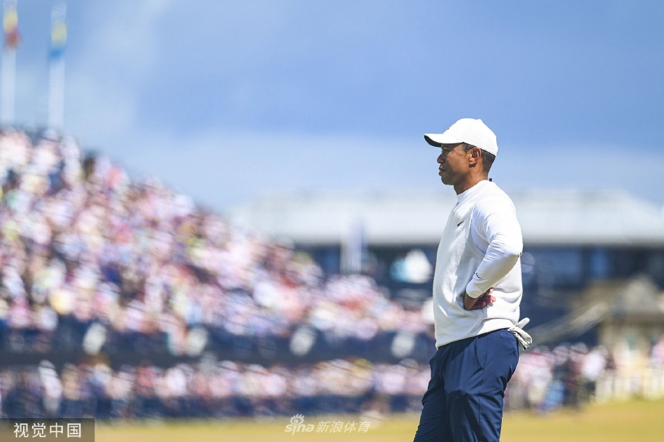 伍兹在果岭边凝神观察推击线路，他微微蹙眉，右手扶腰，展现出竞技者特有的专注与身体承受的负担，气氛凝重而感人