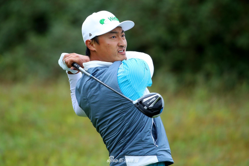 康纳-赛姆在第十八洞果岭凝视远方,手中球帽被大风吹拂,身后是笼罩在雨雾中的凯尔特庄园连绵球场。