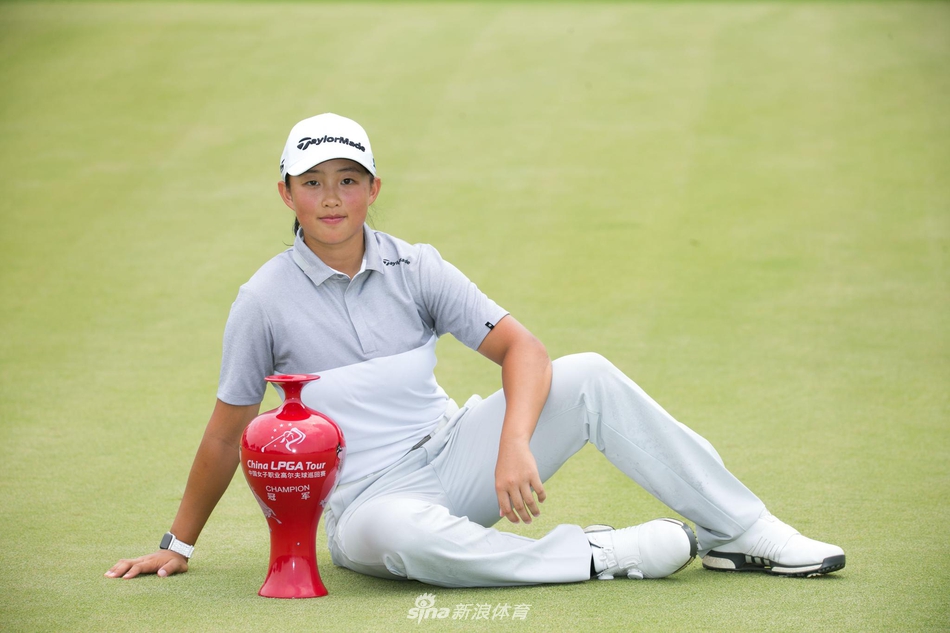 殷若宁在果岭上凝神准备推杆，眼神专注如炬，脚下绿草如茵