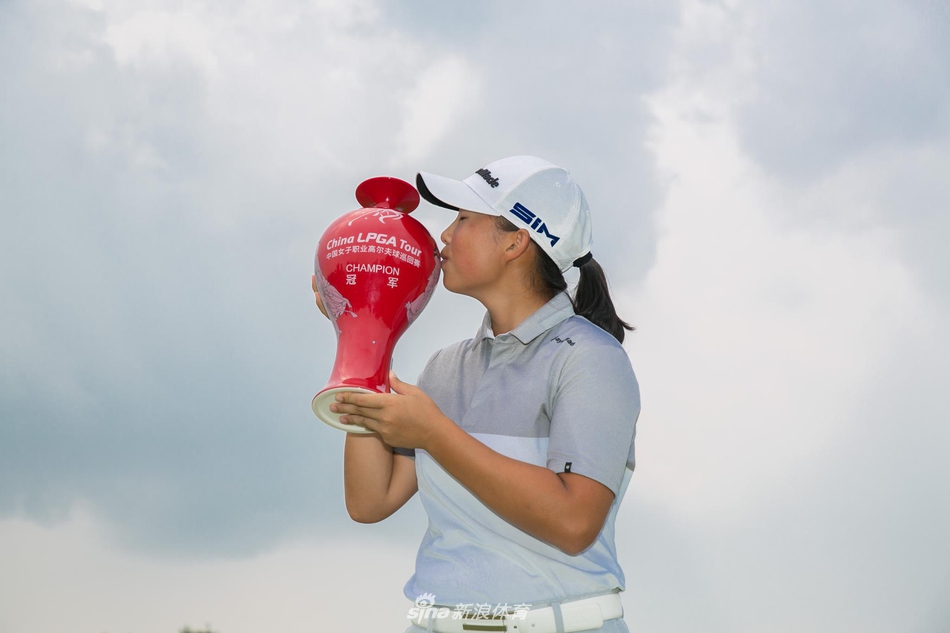 殷若宁手捧冠军奖杯，奖杯在聚光灯下熠熠生辉，见证荣耀时刻