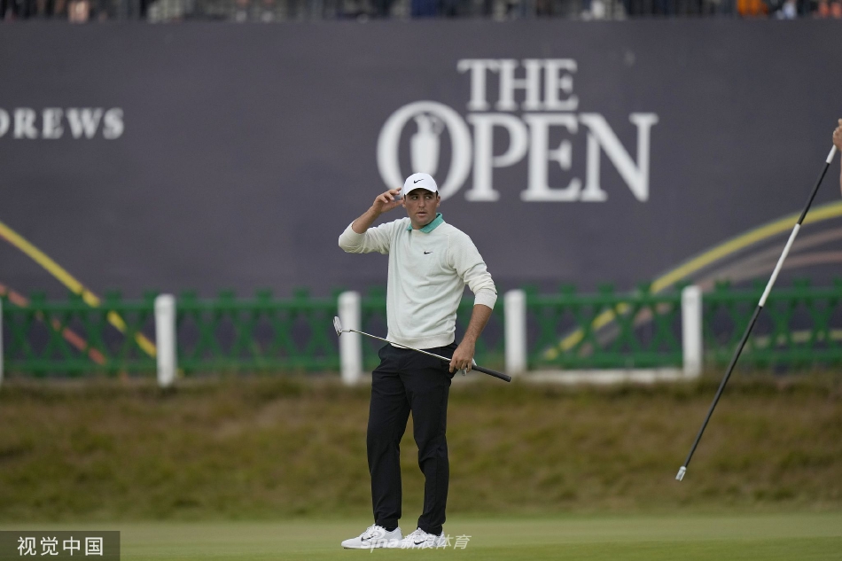 卡梅隆·史密斯高举古老的葡萄酒壶奖杯庆祝胜利，身后是欢呼的人群与著名的圣安德鲁斯皇家古老高尔夫俱乐部会所。